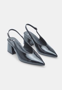 Black patent leather slingback heels with a pointed toe and a block heel. Features a sleek design and adjustable ankle strap.