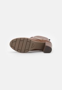 Braune Leder-Schuh mit texturiertem Obermaterial, einem niedrigen Blockabsatz und einer Gummisohle mit horizontalen Rillen für besseren Halt.