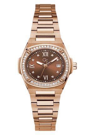 Rose gold metal watch with a brown dial, diamond accents on bezel, and Roman numeral markers. Features a date display at three o'clock.