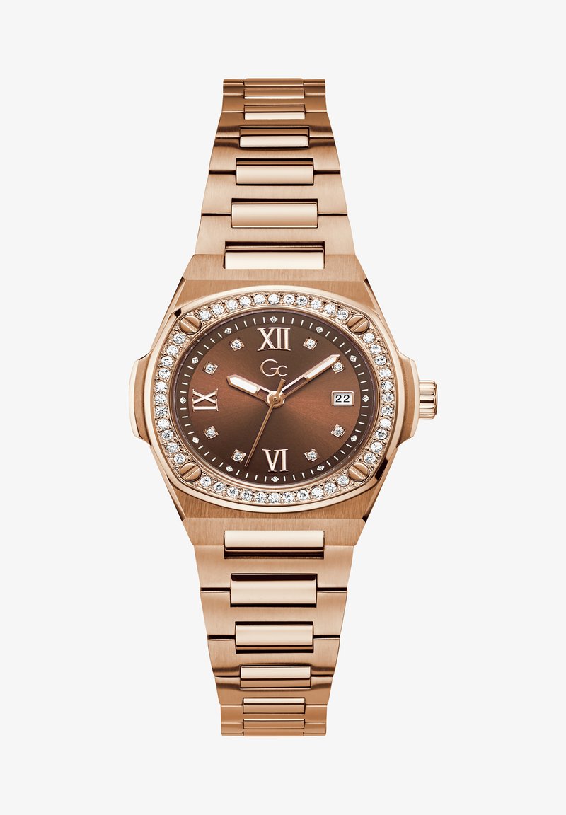Roosa kuldne metallkell pruuni kellaketta, teemantaktsentidega bezel ja rooma numbrimärgid. Omab kuupäeva näidikut kell 3.