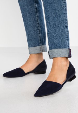Ballerines bleu marine à bout pointu, avec un dessus en daim et un talon texturé, portées avec un jeans en denim retroussé.
