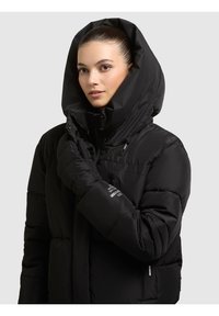 Chaqueta acolchada negra con un gran cuello con capucha, cierre de cremallera y botones, tejido texturizado y un bolsillo en el lado izquierdo con marca.