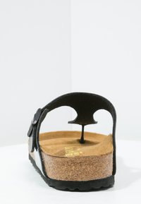 Svart slid-sandal med korkfotbädd, gummisulor och justerbar rem; har en upphöjd häl och öppen baktill design.