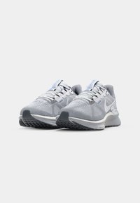 Graue Sportschuhe mit einer strukturierten Oberfläche, hellgrauen Akzenten und einer leicht gepolsterten Sohle. Verfügt über eine Schnürung und ein Logo an der Seite.