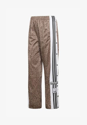 Pantalones deportivos marrones con estampado de jirafa, paneles laterales blancos con rayas negras de Adidas y botones de presión a lo largo de la pierna.