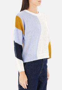 Maglione a blocchi di colore con sezioni blu, bianco, senape e blu navy. Materiale morbido, vestibilità rilassata, scollatura rotonda e polsini a coste.