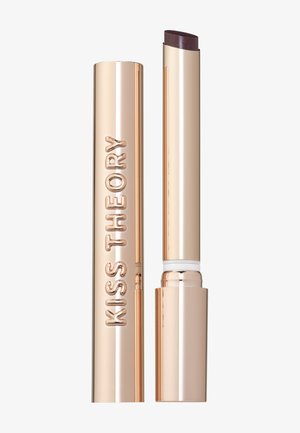 Gouden metalen lippenstifthuls met het label "KISS THEORY", met de dop eraf, waardoor een donkergekleurde lippenstift zichtbaar wordt, op een effen achtergrond.