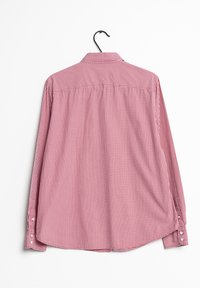 Camicia a maniche lunghe a quadri rossi e bianchi, in tessuto di cotone, con colletto button-down e polsini abbottonati, appesa a un gancio nero.