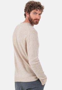 Hellbeiger Strickpullover mit langen Ärmeln, rundem Ausschnitt und gerippten Bündchen. Weiche Textur und dezentes Sprenkelmuster durchgehend.