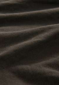 Tessut maro închis, texturat, cu cute și granulație vizibile, prezentând un finisaj mat și un pattern țesut robust.