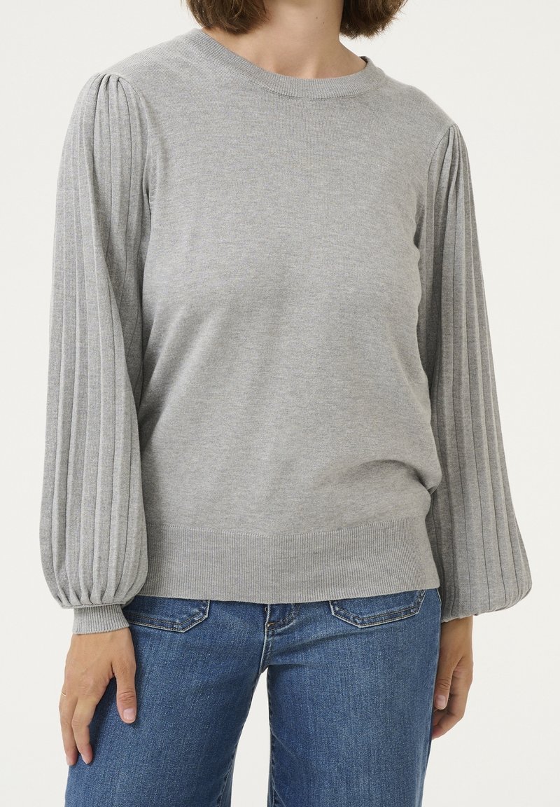 Pull gris avec manches bouffantes côtelées, texture douce, col rond et ourlet ajusté, associé à un jean bleu.