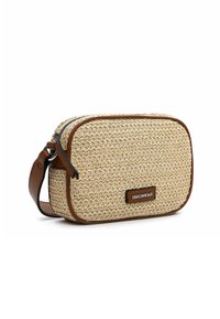 Bolso de paja tejido tipo bandolera en beige natural, con acentos de cuero marrón oscuro, cierre de cremallera y un pequeño parche de logo en la parte delantera.