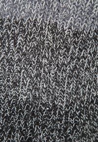 Gros plan d’un tissu tricoté noir et blanc montrant une texture côtelée verticale détaillée.