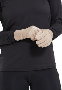 Guanti beige con tessuto strutturato e strisce verticali, indossati da una persona con una maglietta nera a manica lunga. I guanti presentano aperture per le dita e polsini.