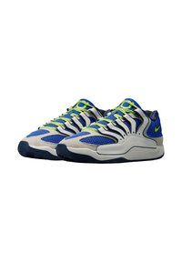 Een paar blauw-witte sportschoenen met neon groene veter en accenten, met mesh en synthetische overlays, zijaanzicht van de Nike-swoosh zichtbaar.