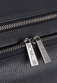 Borsa in pelle nera texturizzata con due cerniere argentate e etichette con logo, che presenta una finitura liscia e opaca con un motivo sottile.