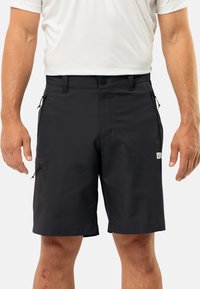 Schwarze Herren-Shorts aus einem glatten, leichten Material. Zu den Merkmalen gehören Taschen mit Reißverschlüssen und ein Patch-Logo auf der rechten Seite.