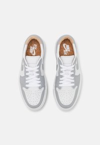 Weiße Leder-Sneaker mit grauen Akzenten, perforierter Zehenbox, weißen Schnürsenkeln, Kork-Innensohle und sichtbarem Markenetikett auf den Innensohlen.