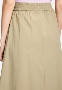 Khaki midi rok met een elastische tailleband, voorzien van een zachte, lichte textuur en een licht geplooid ontwerp aan de achterkant.