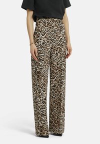 Leopardenmusterige Weitbein-Hose mit beigem Hintergrund und dunkelbraunen Flecken, gefertigt aus einem glatten Stoff mit Seitentaschen.