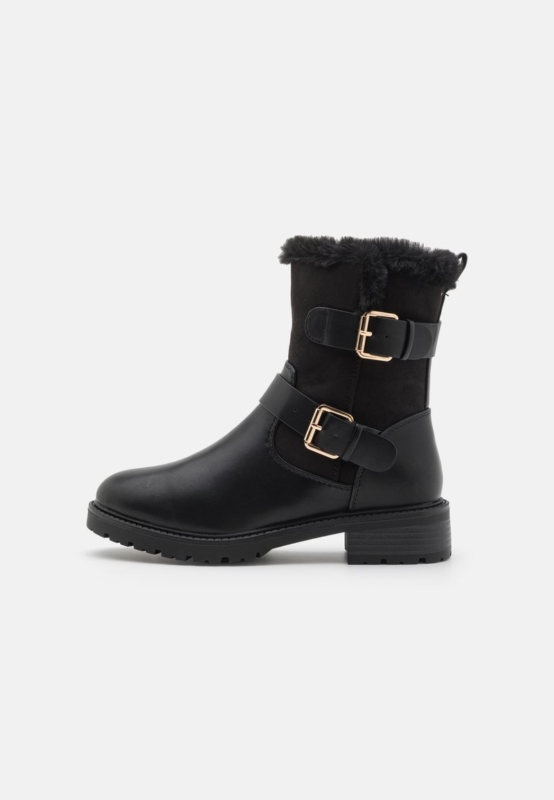 Bottes noires à la cheville en cuir et en suède, avec un parement en fausse fourrure, des accents à double boucle et une semelle en caoutchouc texturé.