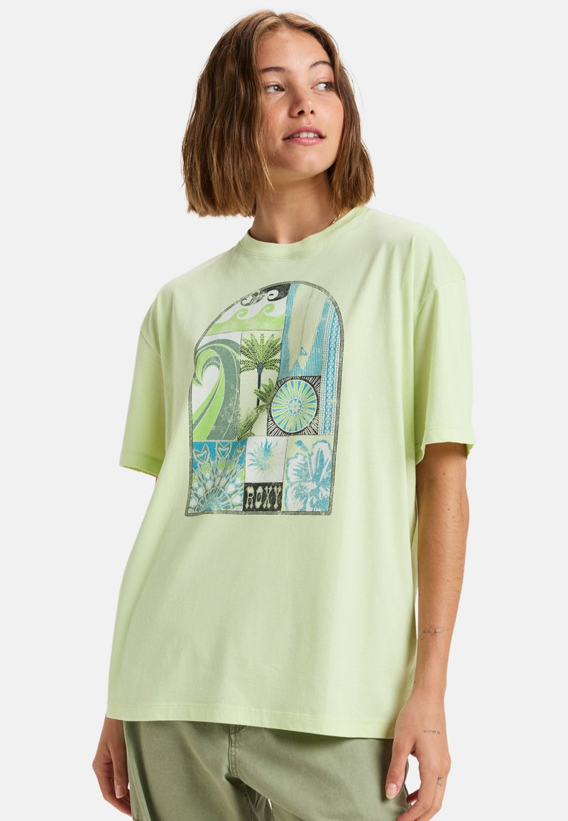 Camiseta de algodón verde claro con un estampado gráfico colorido de palmeras y patrones. Corte holgado, mangas cortas, escote redondo.