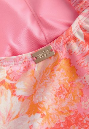 Floral fabric in pink, orange, and white with a smooth texture, featuring a metallic tag attached with floral design details.