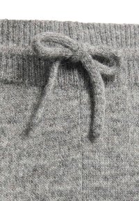 Primo piano di una cintura grigia lavorata a maglia con un cordoncino testurizzato legato a fiocco.