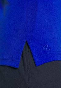 Blå bomullströja med en sidoklyvning vid fållen och sydda detaljer. Har en broderad "RL"-logotyp i matchande nyans.