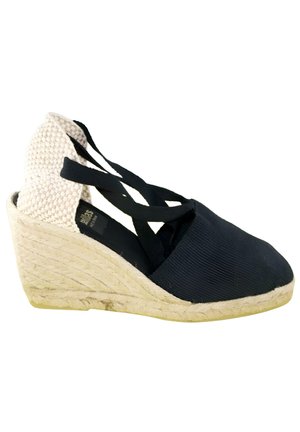 Zapato alpargata con cuña negro y beige con tacón tejido, suela de yute y correas negras entrecruzadas en el tobillo.