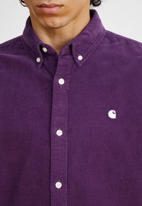 Paarse corduroy shirt met button-down kraag, met witte knopen en een klein wit logo accent op de borst.