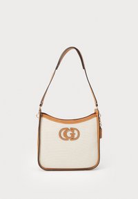 Sac à main en toile beige avec des finitions en cuir marron, présentant une forme incurvée et un logo entrelacé bien en vue sur le devant. Sangle réglable incluse.