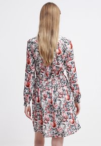 Abito floreale con maniche lunghe, vita elasticizzata e una fantasia colorata con accenti rosa, grigio e nero. Tessuto leggero.