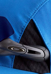 Close-up of a gray clip with a black oval logo attached to a blue and black fabric garment.