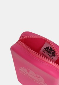 Pochette rosa rettangolare con zip, realizzata in materiale liscio, con il logo SUNDEK ben visibile in bianco e una zip decorata.
