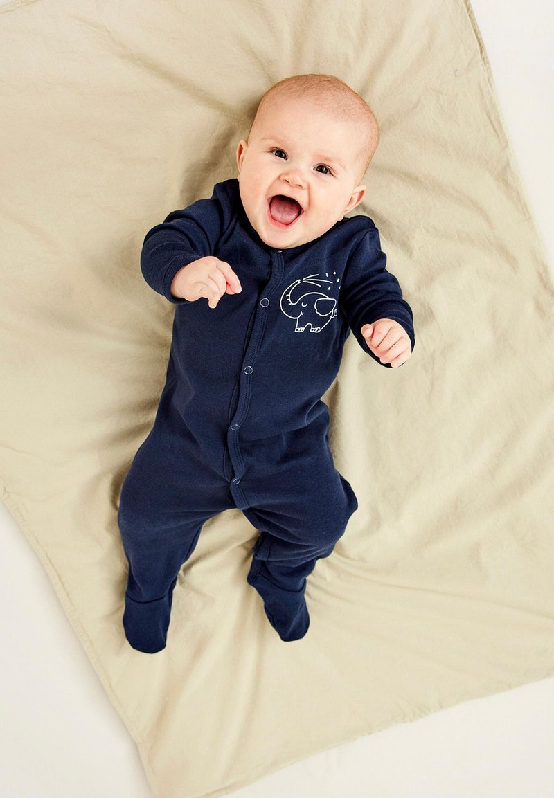 Navyblå bebiskjol med lång ärm och tryckknappar, med en vit elefantgrafik på bröstet, liggande på en beige filt.