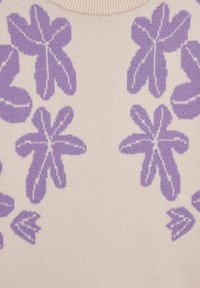 Pletena jopica s kremasto ozadje, ki ima lila cvetni vzorec. Krožen izrez in mehak tekstura z dvignjenimi šivi.