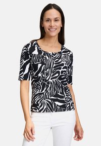 Top a righe zebra in bianco e nero con maniche corte, scollo rotondo e forma aderente, realizzato in un tessuto leggero e testurizzato.
