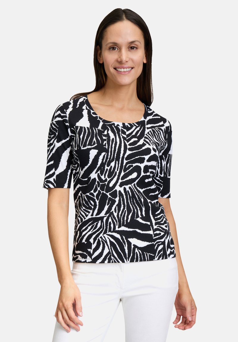 Top a righe zebra in bianco e nero con maniche corte, scollo rotondo e forma aderente, realizzato in un tessuto leggero e testurizzato.