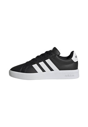 Sneaker Adidas nera low-top con strisce bianche, suola bianca e logo Adidas su tallone e suola intermedia, vista di lato.