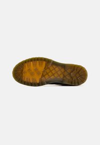 Sort gummisko sål med en tekstureret, mønstret greb. Mellemsålen har en gullig nuance for holdbarhed og greb.