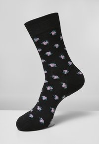 Svarta strumpor med ett stickat blommönster i rosa och grönt, med en bekväm ribbad mudd och strukturerad tyg.