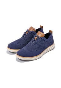 Námořnické modré pletené boty s hnědými koženými akcenty a texturovaným povrchem, disponující lehkou podrážkou a šněrovacím designem.