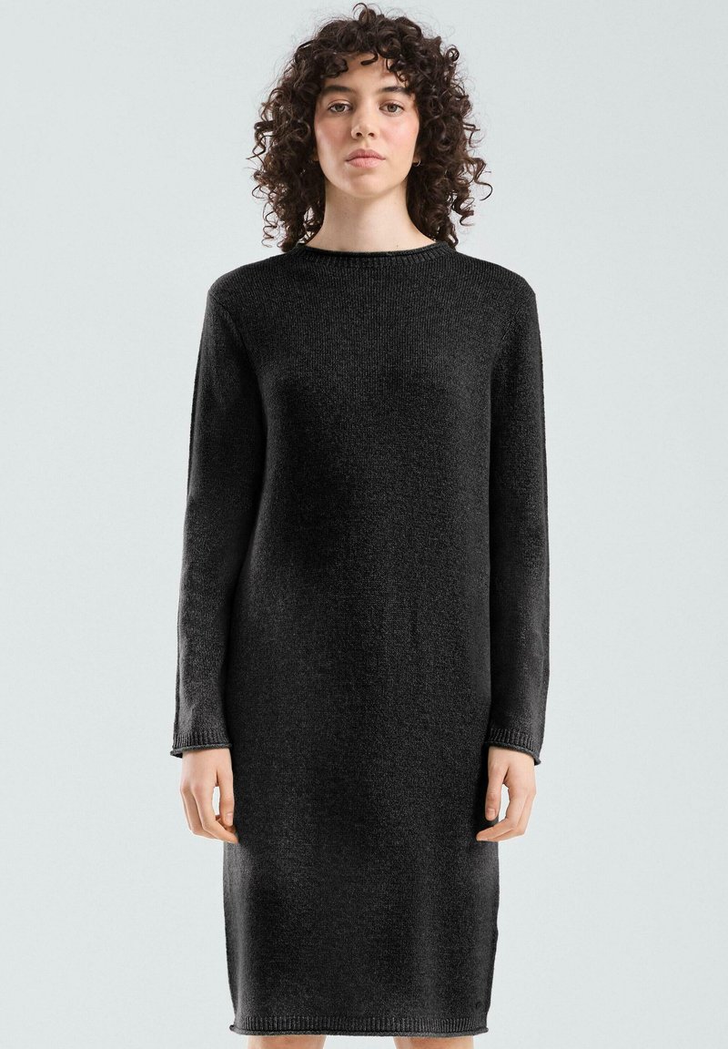 Robe tricotée noire à manches longues, encolure ronde et poignets côtelés. Le tissu a une texture douce et une silhouette droite.