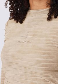 Maglietta a maniche lunghe beige con motivo a righe testurizzato e un piccolo logo ricamato sul petto. Tessuto liscio e elasticizzato.