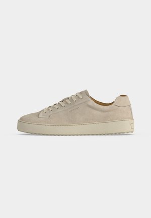Beige ruskind lavtop sneaker med snørelukning og tyk gummisål, vist fra siden på en ensfarvet hvid baggrund.
