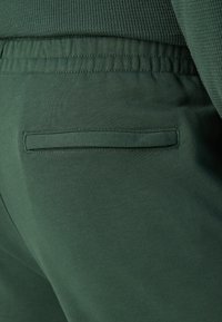 Grønne bomulls joggebukser med strukturert midje, elastiske mansjetter og en skjult baklomme med en sydd detalj.
