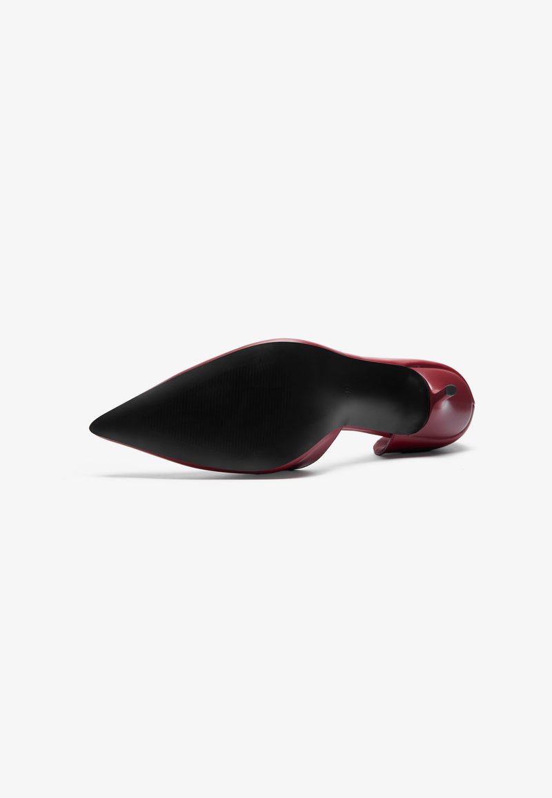 Scarpa col tacco alta rossa con punta affilata e finitura lucida. Suola in gomma nera con grip testurizzato. Design pulito, senza motivi visibili o decorazioni.