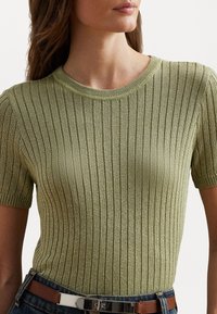 Light green ribbed knit shirt with short sleeves and a round neckline, paired with denim and a brown belt featuring metallic hardware.