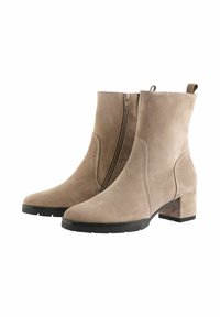 Bottines en daim beige clair avec une fermeture éclair sur le côté, bout arrondi et un talon noir épais. Texture lisse avec un minimum de détails de surface.